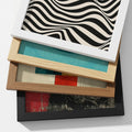 Custom print-on-demand framed poster available in black, white and natural wood frames, stacked to show frame colour options